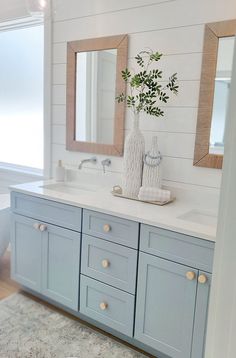 a bathroom with blue cabinets and two mirrors on the wall next to a bathtub