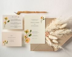 the wedding stationery is laid out on top of an envelope and some flowers are placed next to it