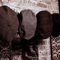 four hats are hanging on a brick wall