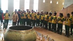 a group of people standing in front of a large vase with gold decorations on it