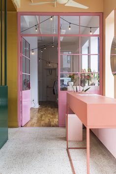 the inside of a pink and yellow shop with lots of windows on each side of the room