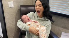 a woman holding a baby in her arms and making a funny face at the camera