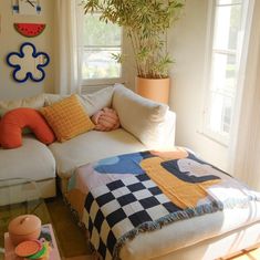 a living room with a couch, coffee table and potted plant in the corner