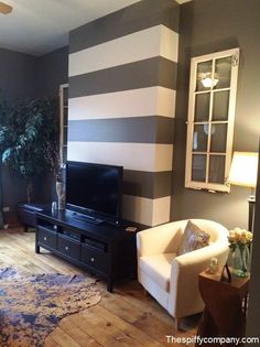 a living room with striped walls and wood floors