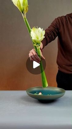 a person arranging flowers in a bowl on a table