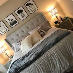 a large bed sitting in a bedroom next to two lamps and pictures on the wall