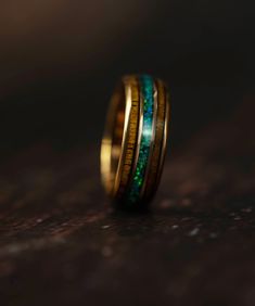 two gold rings with green and blue inlays on the inside of each ring