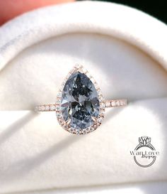 an engagement ring with a pear shaped gray diamond surrounded by white and rose gold diamonds