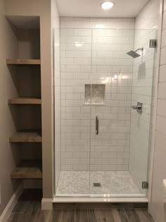 a walk in shower sitting inside of a bathroom next to a shelf filled with shelves