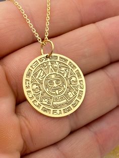 "14k Aztec Calendar Necklace, Personalized Mayan Sun Calendar Pendant, Aztec Coin Pendant, Sun Stone Aztec Calendar Necklace 14k Solid Gold Choose What Size You Want the Pendant Using The First Option Box Choose Chain Length Or Without Chain Using The Second Option Box Photos Are For The 25.4 mm / 1 Inch Diameter Pendant Pendant thickness : 0.7mm  Contact us if you want it thicker Inner diameter of jump ring : 5mm Contact us if you need it bigger  Chain width : 1.30mm     ♥  Material of pendant and chain: Solid Gold k14  ♥  Packaging: All of our jewelry are beautifully boxed and ready for gifting For more personalized designs take a look here: ♥ www.etsy.com/listing/736955132 ♥ www.etsy.com/listing/819494857 ♥ www.etsy.com/listing/823397880 ♥ www.etsy.com/listing/769847320 ♥ www.etsy.com/l Yellow Gold Symbolic Engraved Coin Necklace, Handmade 14k Gold Amulet Necklace, Artisan Yellow Gold Medallion Jewelry, Handmade 14k Gold Round Pendant Jewelry, Artisan Engraved Necklaces For Anniversary, Symbolic 14k Gold Necklace With Coin Pendant, Spiritual 14k Stamped Pendant Jewelry, Spiritual 14k Stamped Round Pendant Jewelry, 14k Gold Symbolic Coin Pendant Necklace