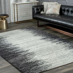 a black and white rug in a living room next to a couch with pillows on it