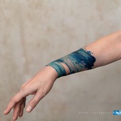 a person's arm with blue paint on it and one hand reaching out towards the camera