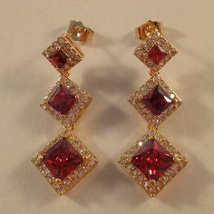 Beautiful Women's "Trilogy Luxury Design" Princess Cut Square Halo Garnet Ruby Red Zircon Drop Dangle Stud Earrings 18k Yellow Gold Filled + Tagged 925 Silver. Trilogy Three Sizes Ruby Red Square Shape Simulated Diamond Topaz Zircon Gemstones. Top Quality, High Polished Shine, Brand New, Never Been Worn. Lead, Nickel Free. These Gorgeous Earrings Sparkle. The "Trilogy" Design Represents Different Things To Different People - Past, Present, And Future, Relationships, Three Years Together, Three S Red Chandelier Earrings As Gift, Red Chandelier Earrings For Anniversary, Red Cubic Zirconia Earrings For Gift, Red Ruby Dangle Chandelier Earrings, Red Chandelier Earrings For Formal Events, Formal Red Chandelier Earrings, Formal Red Cubic Zirconia Earrings, Red Dangle Chandelier Earrings For Anniversary, Red Ruby Dangle Earrings