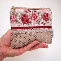 a hand holding a small purse with flowers on it