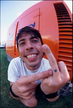 a man making the peace sign in front of an orange object with his fingers up