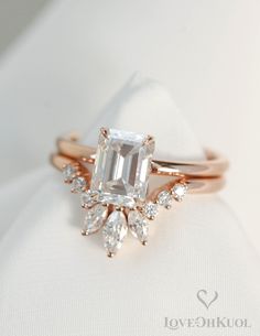 an emerald and diamond ring on top of a white cloth