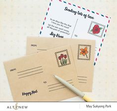 two envelopes with stamps on them next to a pen