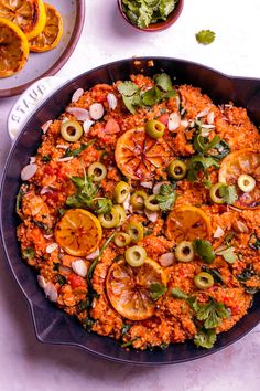 a pan filled with rice and vegetables on top of a white table next to other dishes