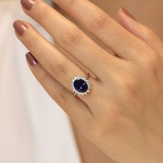 a woman's hand with a ring on it and a blue stone in the middle