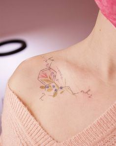 a woman with a tattoo on her shoulder is looking down at the ground while wearing a pink sweater