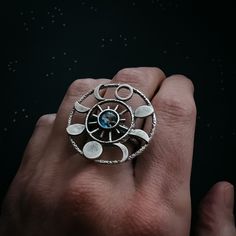 "What a knockout! This textured gold or silver tone ring is set with the Earth in glass surrounded by 8 different phases of the moon in a round halo. Celebrate the cosmos and our planetary home with this piece of galaxy jewelry! Ring Size: Adjustable Design Size: 1 1/4\" (3.2cm) Materials: brass, glass ★ These are individually handcrafted and the particular piece you receive may vary slightly from what is pictured. These are also not 100% waterproof, so please avoid submerging them in water. ★ D Celestial Open Ring With Moon Phase Detail, Nickel-free Celestial Moon Ring, Celestial Moon Phase Open Ring Jewelry, Celestial Moon Phase Open Ring, Silver Moon Shaped Celestial Crystal Ring, Silver Moon Phase Crystal Ring, Celestial Moon Phase Crystal Ring, Celestial Metal Ring Jewelry, Celestial Style Metal Ring Jewelry