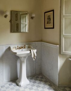 a white pedestal sink sitting under a bathroom mirror