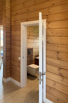 an open door leading to a bathroom with wood paneling on the walls and floor