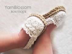 a hand is holding a crocheted slipper in white and brown yarn, with the word yarn blossom boutique written on it