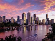 a boat is traveling on the water in front of some tall buildings at sunset or dawn