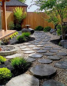 an outdoor garden with stepping stones and plants in the center, surrounded by wooden fence