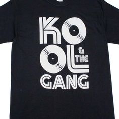 Kool & The Gang Records Logo Rap Hip Hop Throwback Retro Rock N Roll Concert Short Sleeve Tee Shirt. Adult Size Shirt Made From 100% Pre-Shrunk Medium Weight Cotton. Every Item We Sell Is Original Brand New. If An Item Is Designated As "Distressed", The Design Contains Intentional Skips And Voids Which Give The Item A Worn-In Or Vintage Look. These Are Part Of The Actual Design And Do Not Reflect Poor Printing. Cool Black Cotton T-shirt, Cool Black Crew Neck Top, Cool Black Tops With Graphic Design, Cool Black Top With Crew Neck, Cool Black Top With Graphic Print, Black Fan Merchandise Shirt For Summer, Black Fan Merchandise Summer Shirt, Cool Black T-shirt With Graphic Print, Retro Black Tops With Text Print