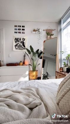 a bedroom with a bed, mirror and plants