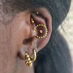 a close up of a person wearing ear piercings with green dots on the side