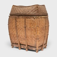 an old woven basket with wooden handles on the top and bottom, sitting on a white surface