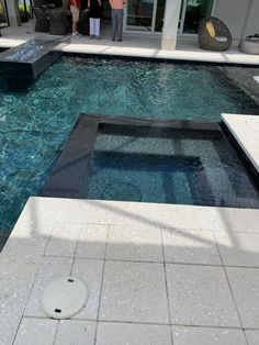 two people standing next to a swimming pool