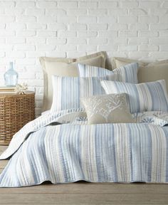 a bed with blue and white striped comforter next to a wicker basket on the floor