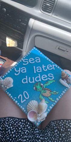 a woman is wearing a blue graduation cap with shells on it and the words sea ya later dudes 20