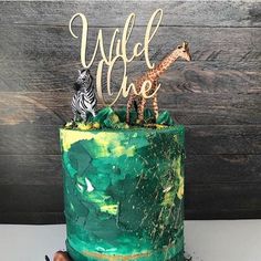 there is a cake decorated with green icing and two giraffes on top