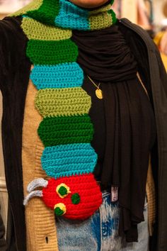 a woman wearing a scarf with a crocheted caterpillar on it