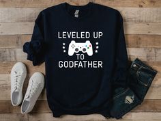 a sweatshirt that says level up to godfaither on it next to jeans and sneakers