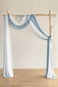 an arch made out of branches with blue and white drapes