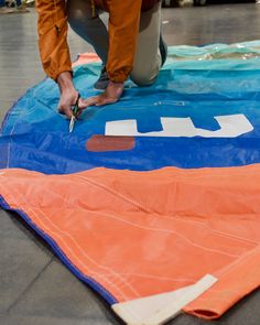 a man is working on an orange and blue kite