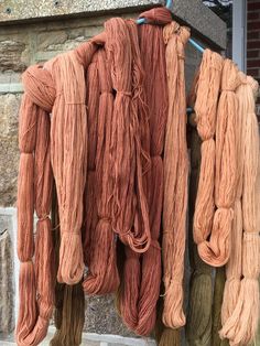 several skeins of yarn hanging on a clothesline outside an old brick building