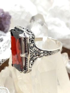 Garnet Cubic Zirconia (CZ) Sterling Silver Ring 1915 Design#D232 This is a lovely antique Edwardian era inspired filigree ring. This gorgeous ring is set with a stunning garnet cubic zirconia (CZ) gem. The vibrant gemstone is 18mm x 9mm. The ring sits 21mm north-south and 12mm east-west on the finger. The inside of the band is marked 925 for solid sterling silver. The band and setting have intricate filigree, with hints of floral influence across it. This amazing ring is a reproduction of a ring Dream Wedding Ring, Edwardian Jewelry, Garnet Ring, Edwardian Era, Filigree Ring, Cz Ring, Engraved Items, Garnet Rings, Red Garnet