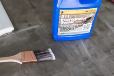 a paint can and brush sitting on the ground next to a tile floor that has been cleaned