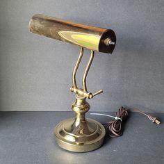 an antique brass desk lamp sitting on top of a table next to a charger