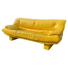 a yellow leather couch sitting on top of a wooden table