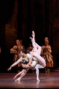 two ballerinas are performing on stage with their arms in the air and one is holding