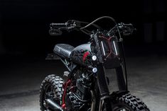 a black motorcycle parked in the dark with red accents on it's front tire