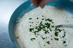 a blue bowl filled with white sauce and chopped parsley